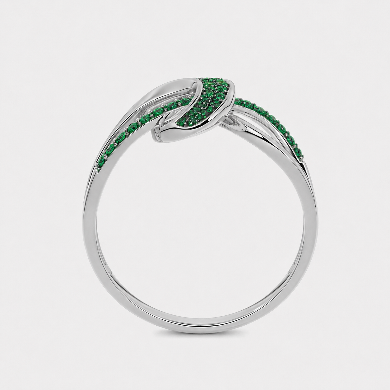 Angled view of silver-tone abstract swirl ring with emerald green stone accents