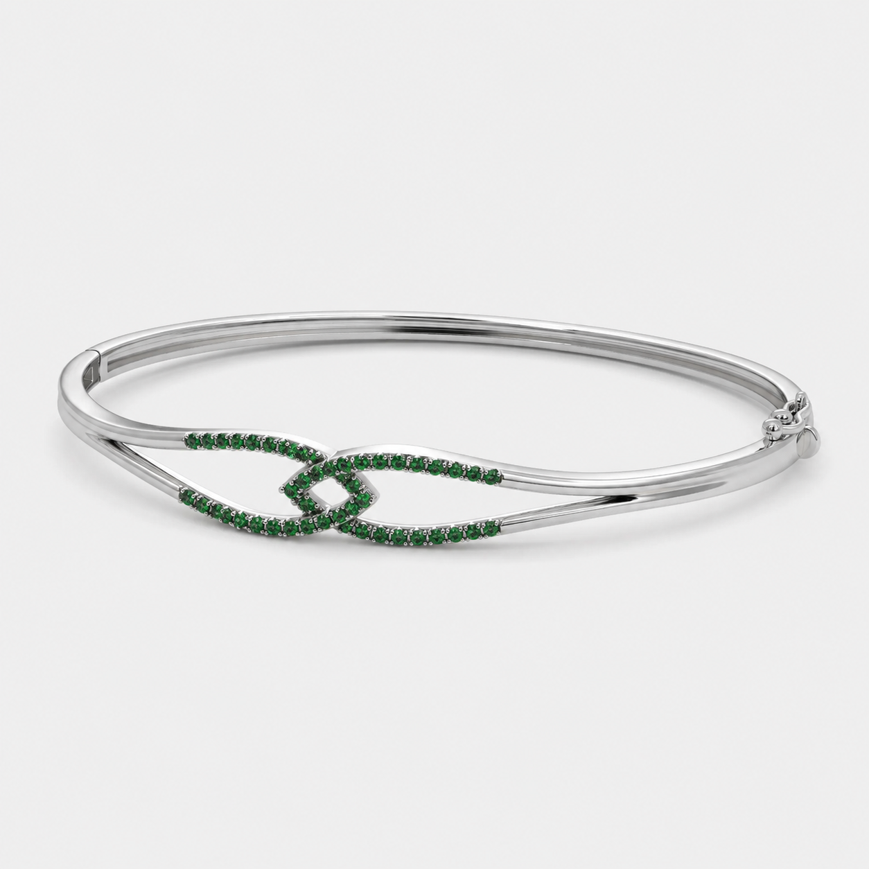 Angled view of silver-tone cuff bracelet with emerald green stone accents and polished finish