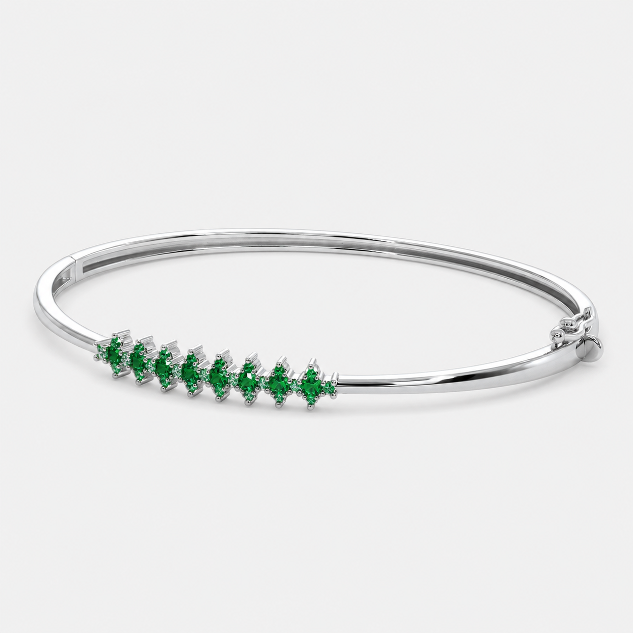 Front view of silver-tone bangle bracelet featuring emerald green marquise-cut cubic zirconia accents