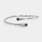 Angled view of silver-tone cuff bracelet with emerald green stone accents and polished