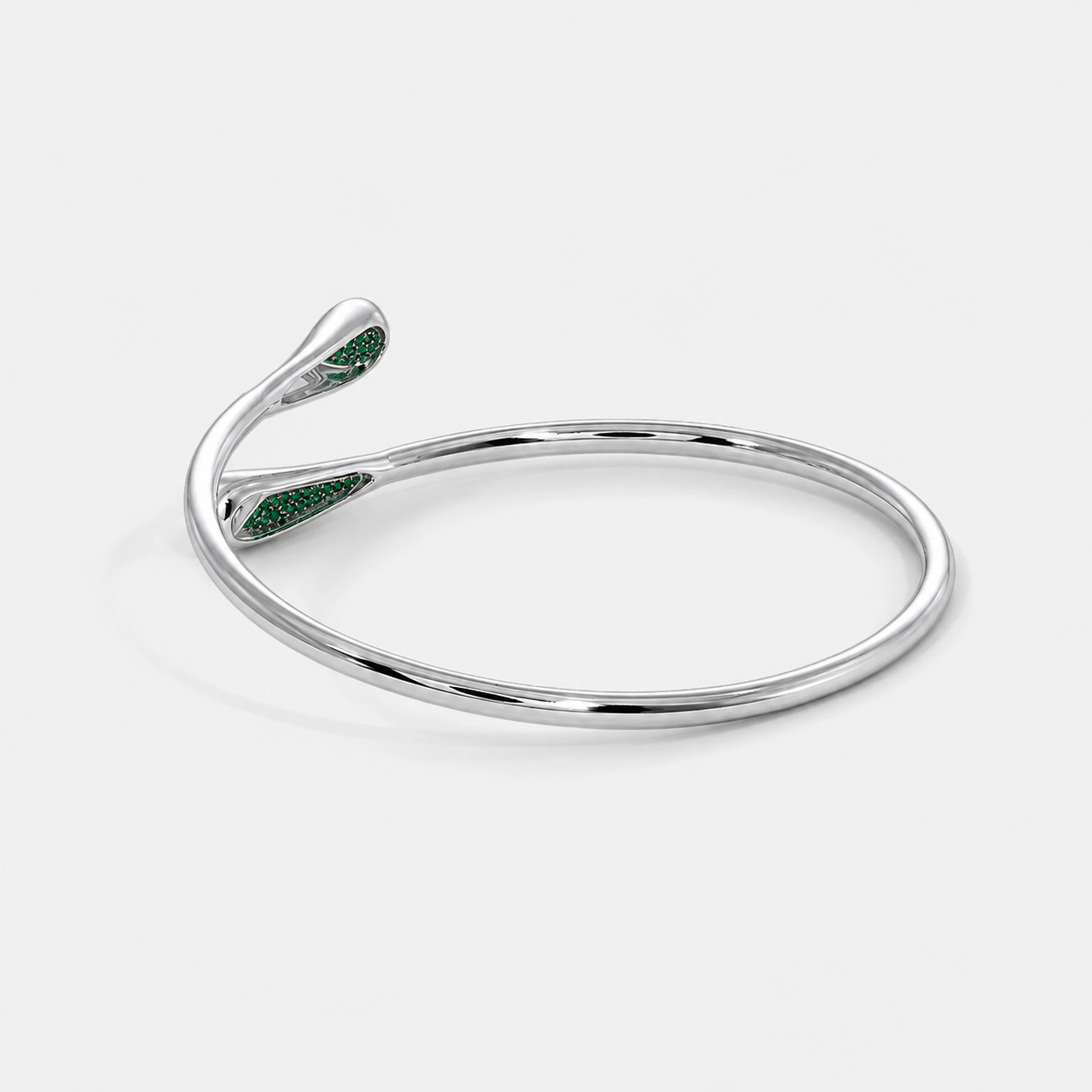 Side perspective of silver-tone open bracelet showcasing emerald green pavé cubic