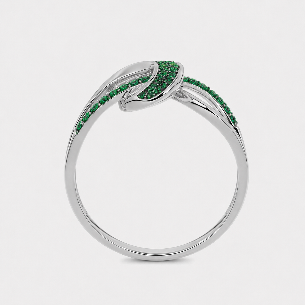 Angled view of silver-tone abstract swirl ring with emerald green stone accents