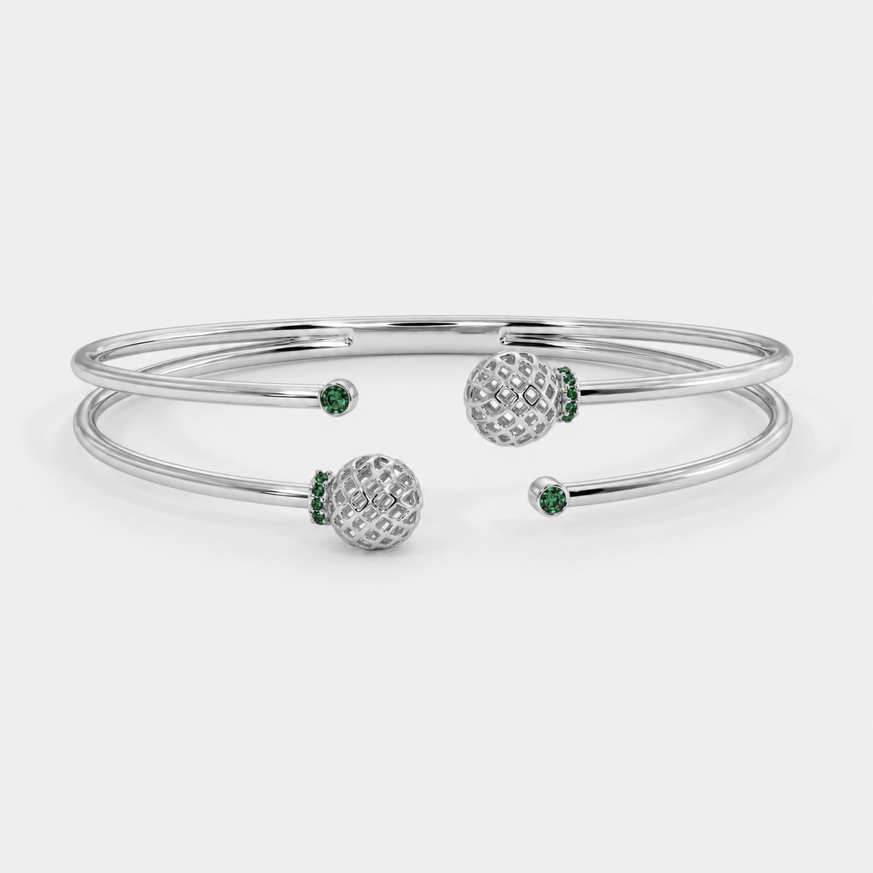 Angled view of silver-tone bracelet with dual band design, openwork spheres, and emerald green stone accents