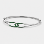 Angled view of silver-tone cuff bracelet with emerald green stone accents and polished finish