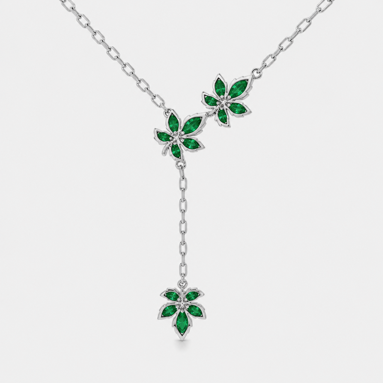Angled view of silver-tone floral station necklace with multiple emerald green gemstone-inspired details and adjustable chain