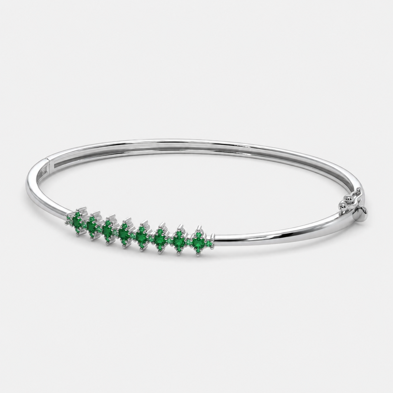 Angled view of silver-tone hinged bangle bracelet with emerald green marquise-cut cubic zirconia stones