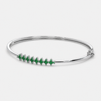 Angled view of silver-tone hinged bangle bracelet with emerald green marquise-cut cubic zirconia stones