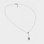 Angled view of silver-tone necklace with emerald green teardrop cubic zirconia pendant and adjustable extension chain
