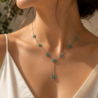 Close-up detail of emerald green floral accents and drop pendant centerpiece on silver-tone necklace