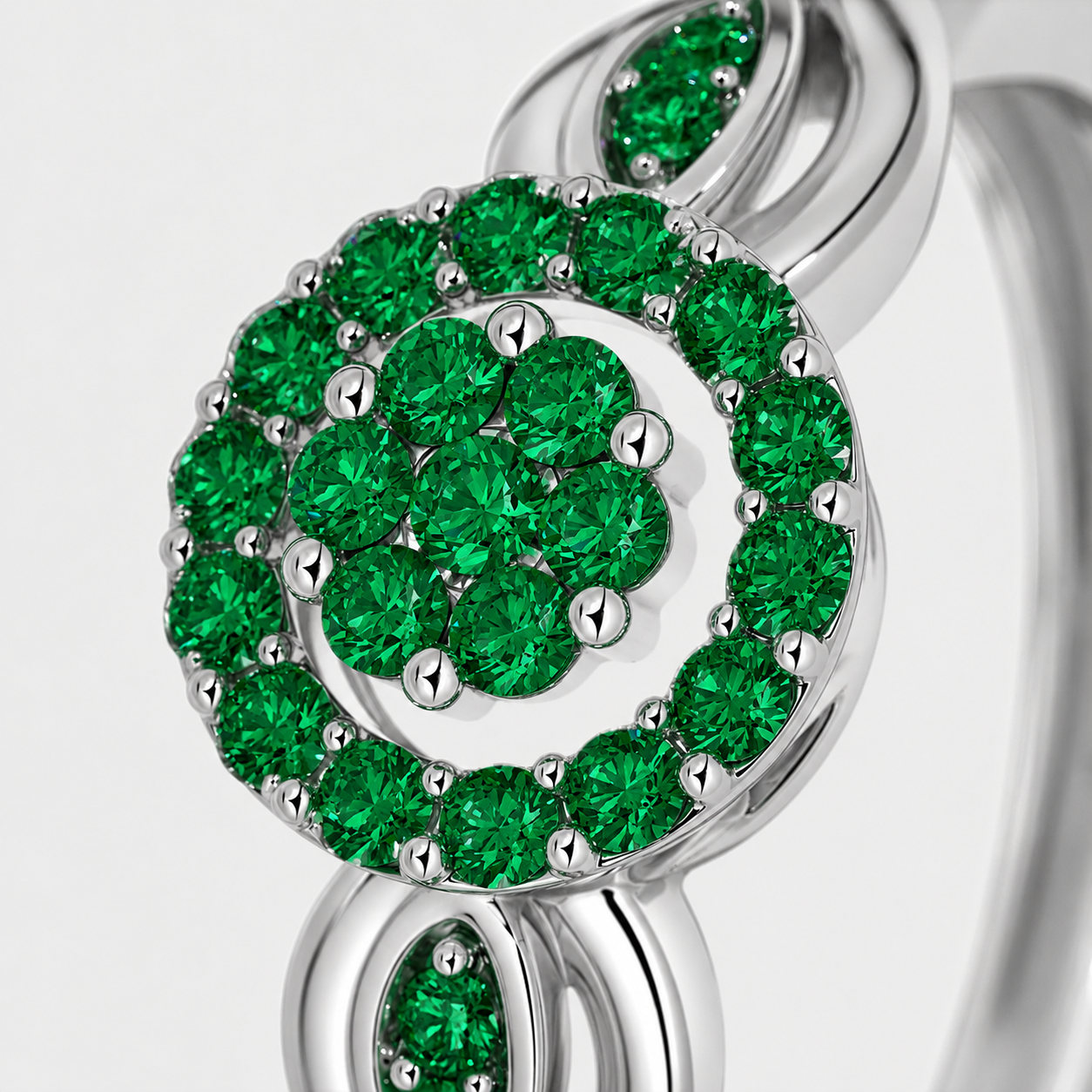 Close-up detail of emerald green floral halo centerpiece on silver-tone ring with decorative leaf accents