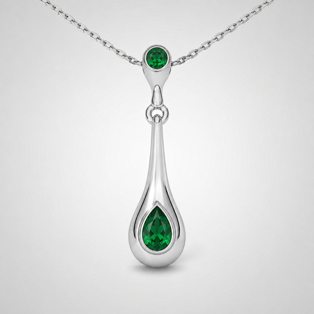 Close-up view of emerald green teardrop pendant suspended from a fine silver-tone chain