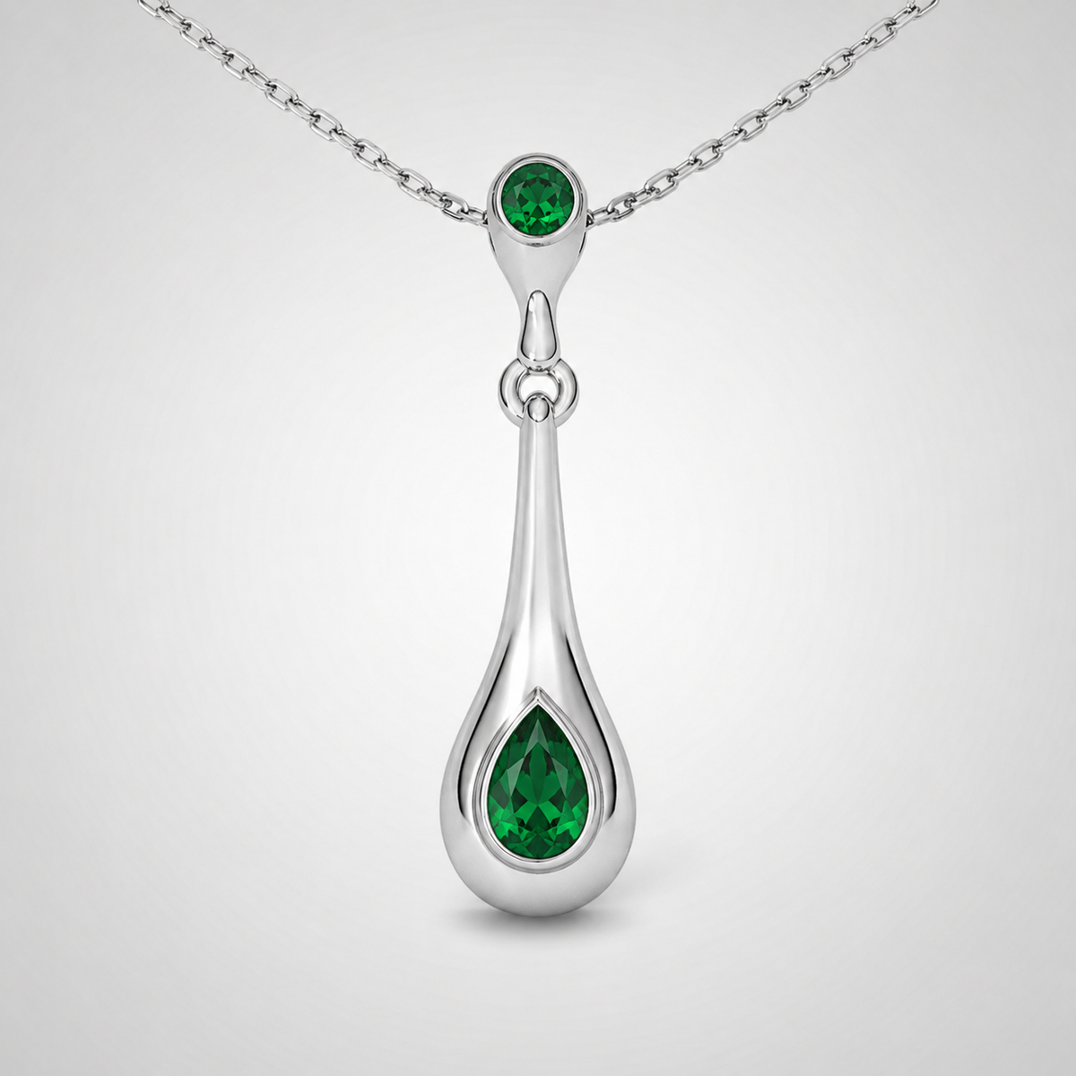 Close-up view of emerald green teardrop pendant suspended from a fine silver-tone chain