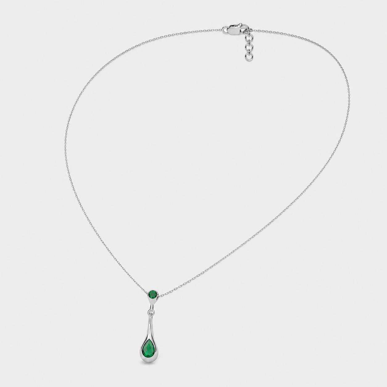 Front view of silver-tone pendant necklace featuring faceted emerald green teardrop cubic zirconia charm