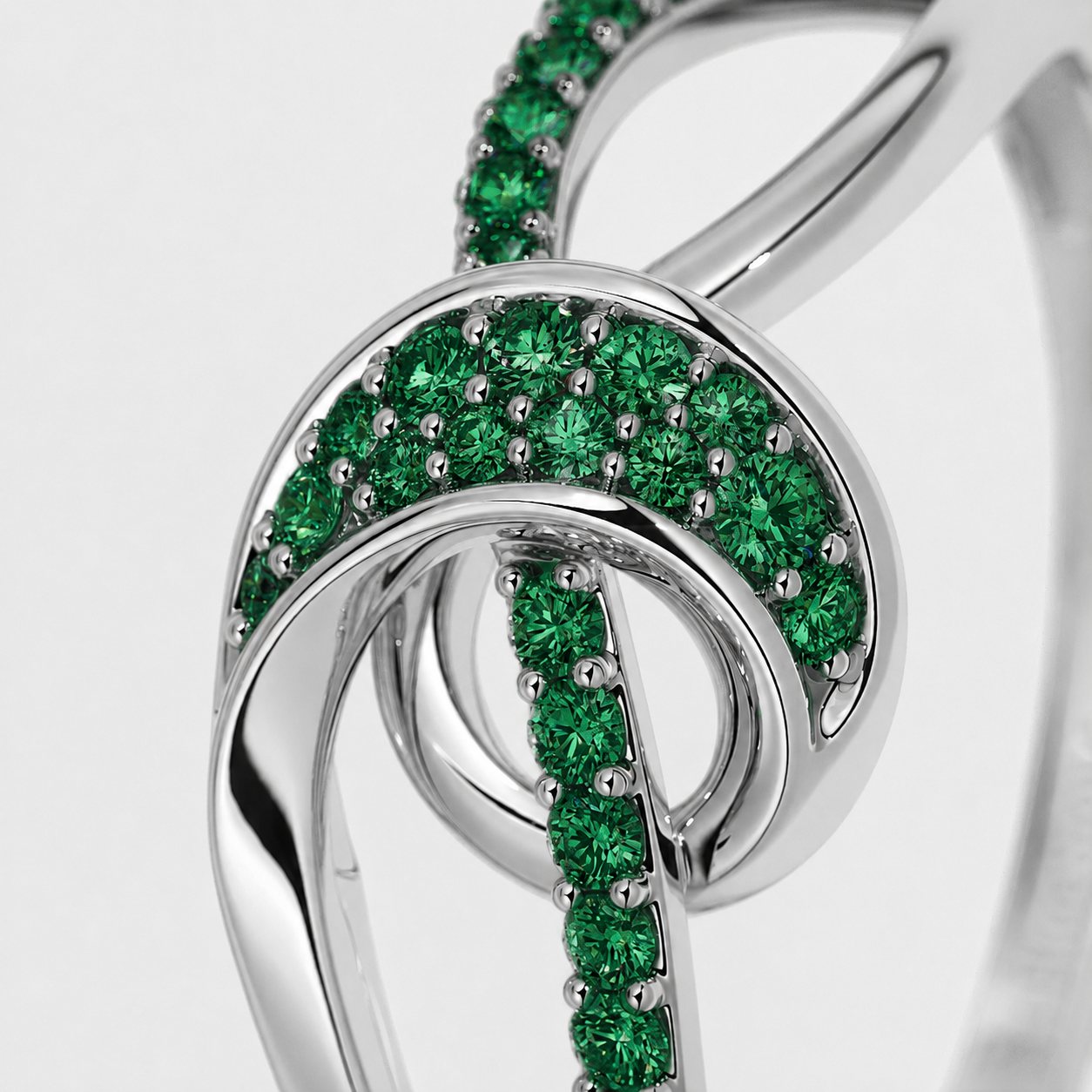 Front view of silver-tone statement ring featuring an abstract swirl design with emerald green cubic zirconia accents