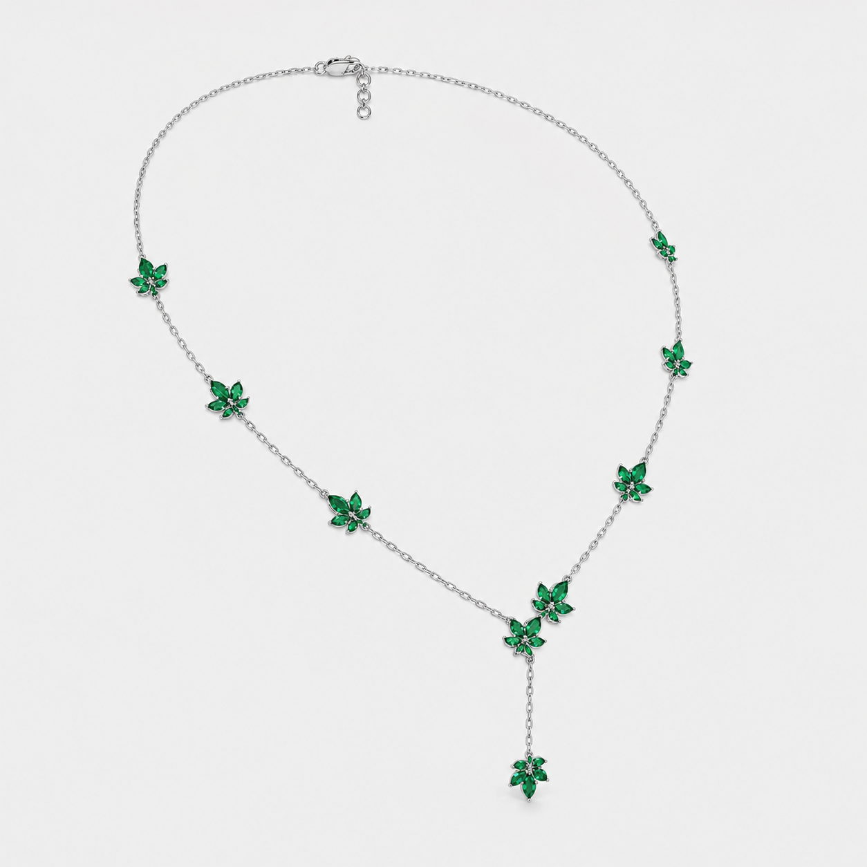 Front view of silver-tone station necklace featuring emerald green floral cubic zirconia accents and drop pendant design