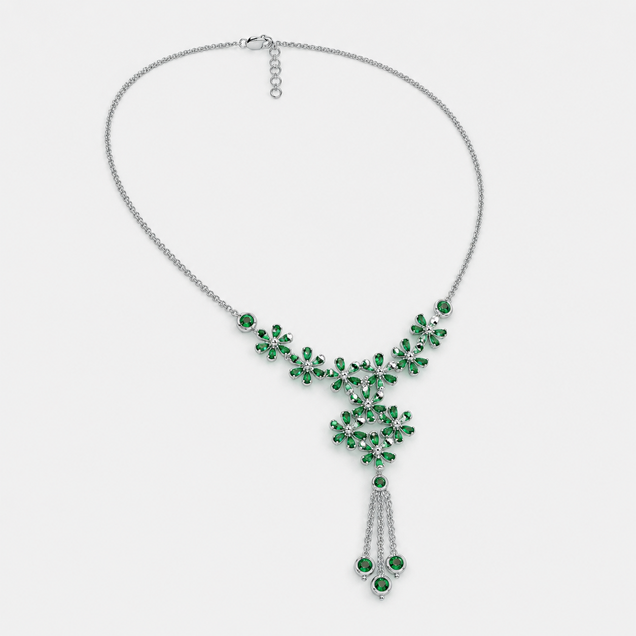 Side angle view of silver-tone statement necklace showcasing floral emerald green cubic zirconia design and tassel detail
