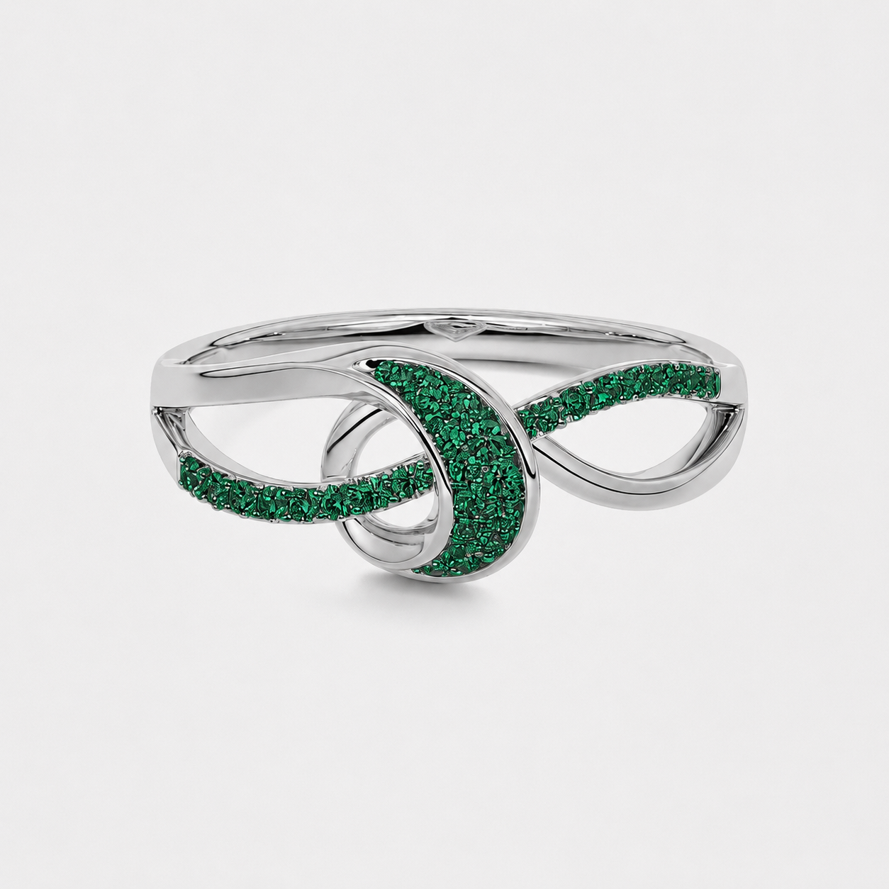 Side profile of silver-tone statement ring featuring an openwork swirl design and emerald green cubic zirconia stones