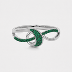 Side profile of silver-tone statement ring featuring an openwork swirl design and emerald green cubic zirconia stones