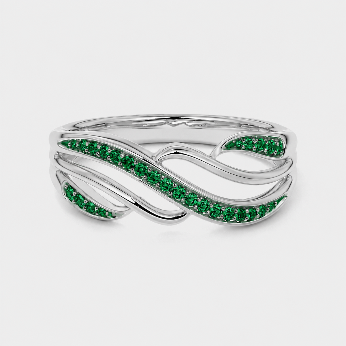 Top view of silver-tone ring showcasing flowing leaf-inspired design with emerald green stones